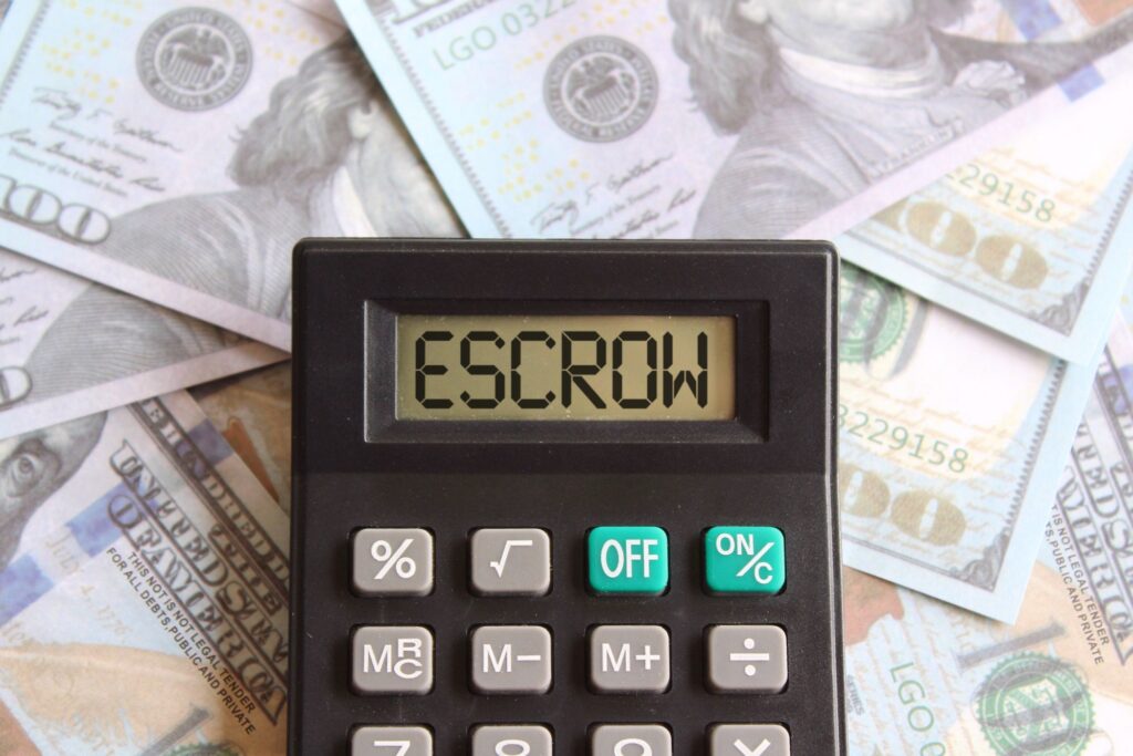 Top view image of money and calculator with text ESCROW on display.